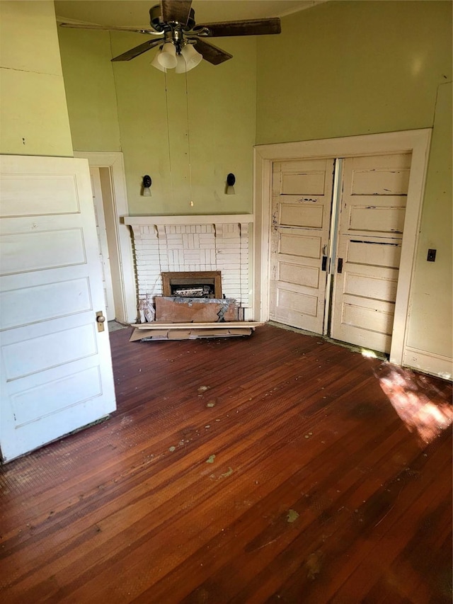 unfurnished living room with a fireplace, ceiling fan, and wood-type flooring