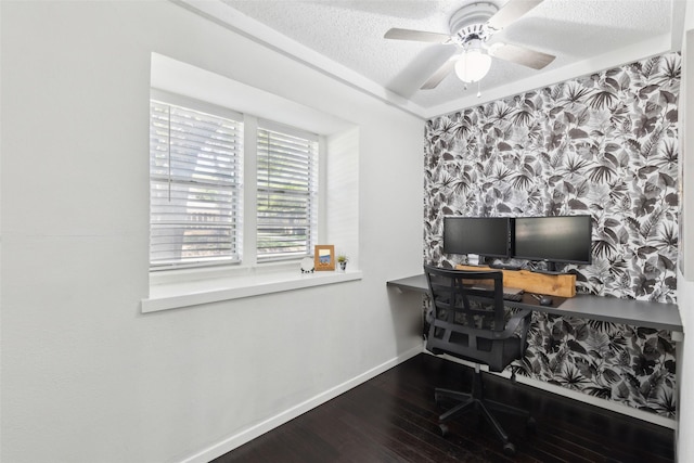 office space featuring an accent wall, a ceiling fan, wood finished floors, a textured ceiling, and baseboards