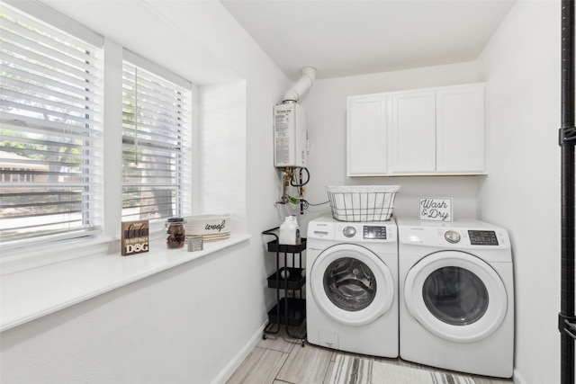 clothes washing area featuring water heater, a wealth of natural light, cabinet space, and washer and clothes dryer
