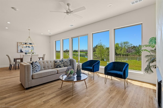 living room with recessed lighting, light wood-style floors, and a water view