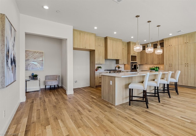 kitchen featuring light wood-style flooring, light brown cabinetry, a kitchen bar, modern cabinets, and light countertops