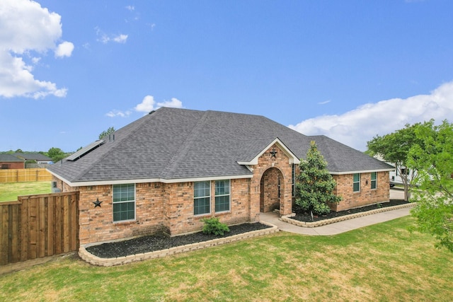 view of front facade featuring brick siding, a shingled roof, and a front lawn