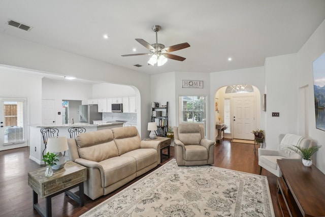 living area with visible vents, a healthy amount of sunlight, ceiling fan, arched walkways, and dark wood finished floors