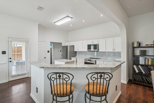 kitchen with crown molding, a center island, stainless steel appliances, and dark wood finished floors