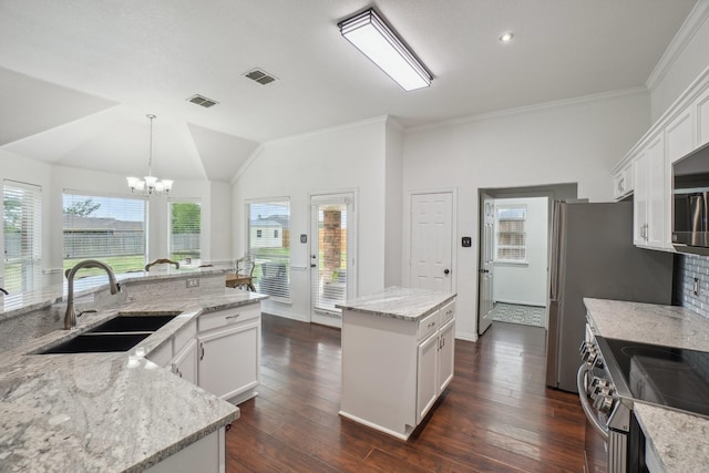 kitchen with lofted ceiling, a kitchen island, white cabinetry, a sink, and appliances with stainless steel finishes