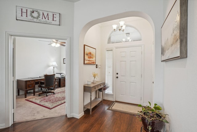 entryway featuring arched walkways, baseboards, dark wood-style floors, and a notable chandelier