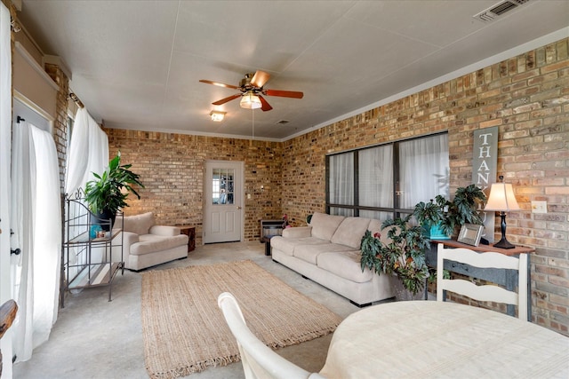 living area featuring ceiling fan, concrete flooring, brick wall, and visible vents