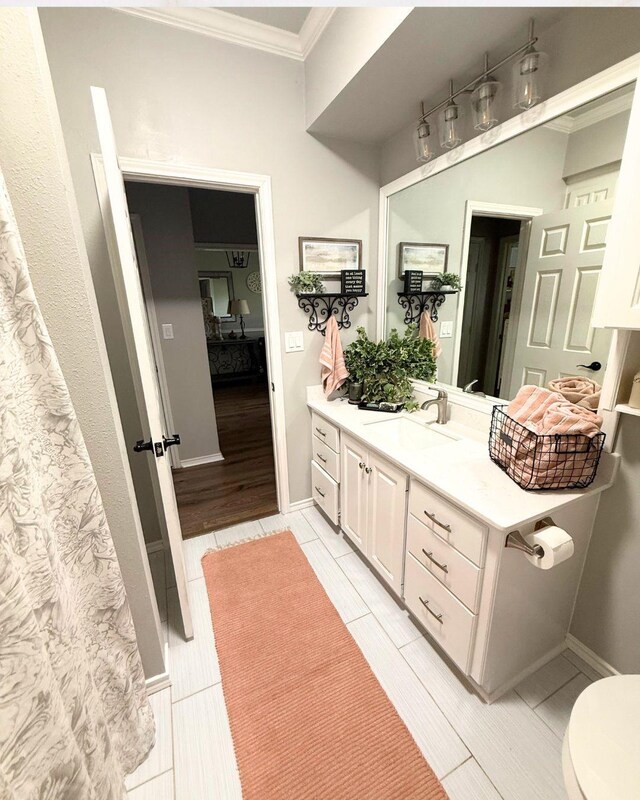 full bath featuring vanity, ornamental molding, and toilet
