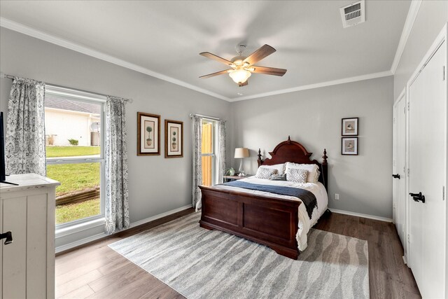 bedroom featuring crown molding, wood finished floors, and multiple windows