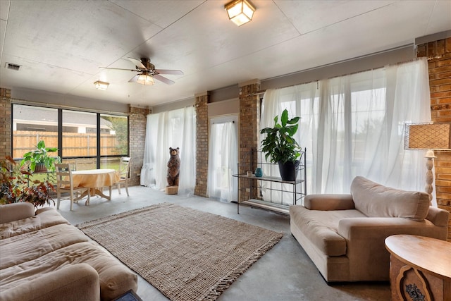 living room featuring brick wall, ceiling fan, finished concrete floors, and visible vents