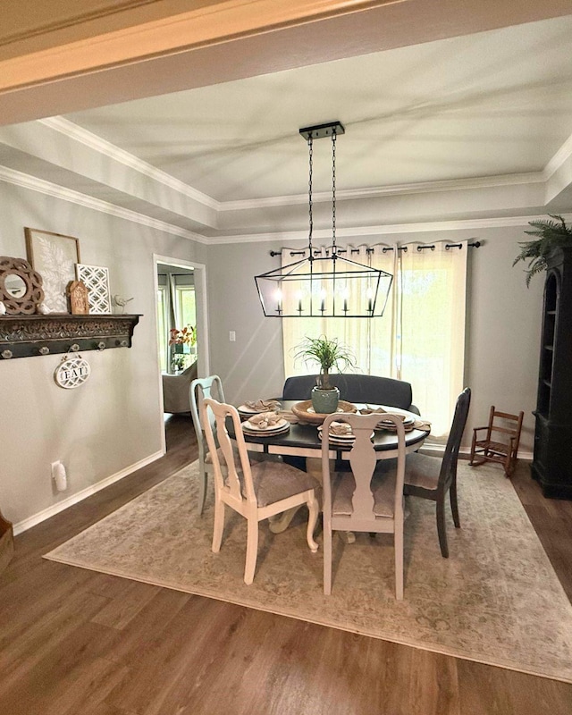 dining room featuring baseboards, ornamental molding, a raised ceiling, and dark wood-type flooring