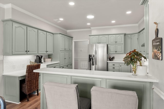 kitchen with crown molding, visible vents, a peninsula, stainless steel fridge, and light wood-type flooring