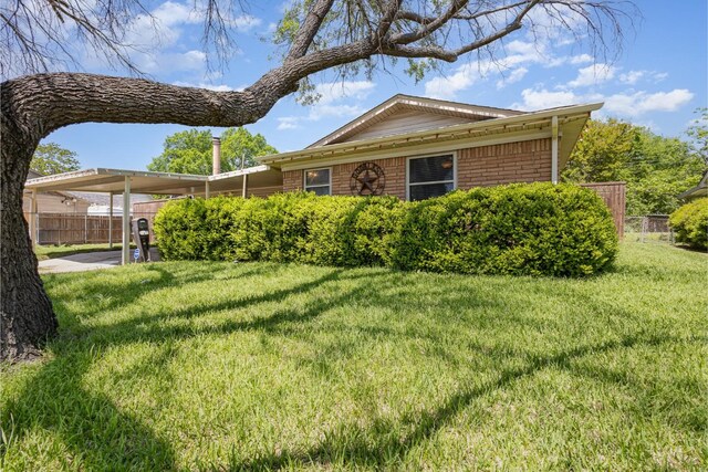 ranch-style home with brick siding, fence, driveway, and a front yard