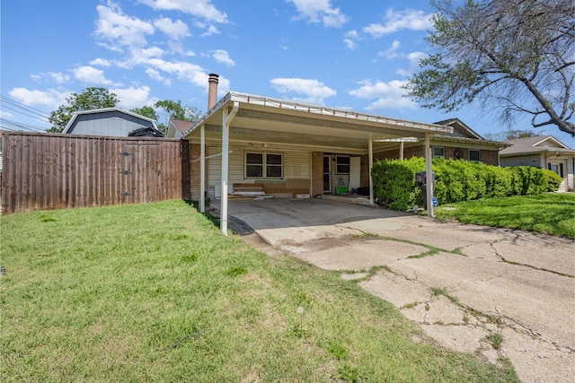 back of house with a yard, fence, driveway, and a carport