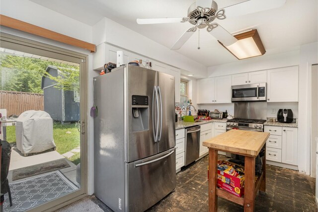 kitchen with white cabinets, a sink, butcher block countertops, stainless steel appliances, and a ceiling fan
