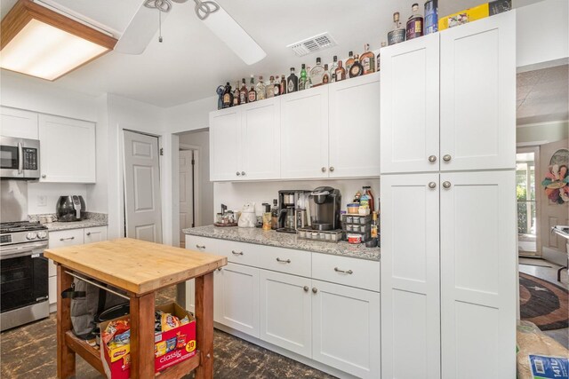 kitchen featuring white cabinets, ceiling fan, light stone countertops, stainless steel appliances, and decorative light fixtures