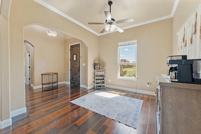 living area with arched walkways, ceiling fan, dark wood-style floors, and ornamental molding