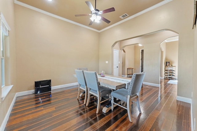 dining room with arched walkways, visible vents, a ceiling fan, dark wood-type flooring, and ornamental molding