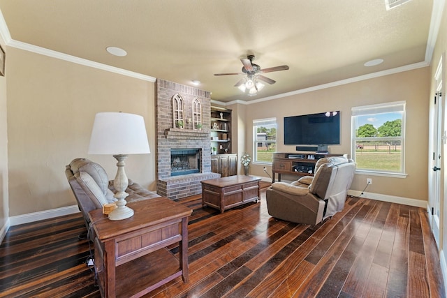 living area with dark wood finished floors, a ceiling fan, ornamental molding, baseboards, and a brick fireplace