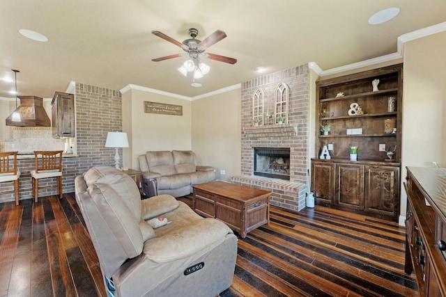 living area with a ceiling fan, dark wood-style flooring, crown molding, and a fireplace