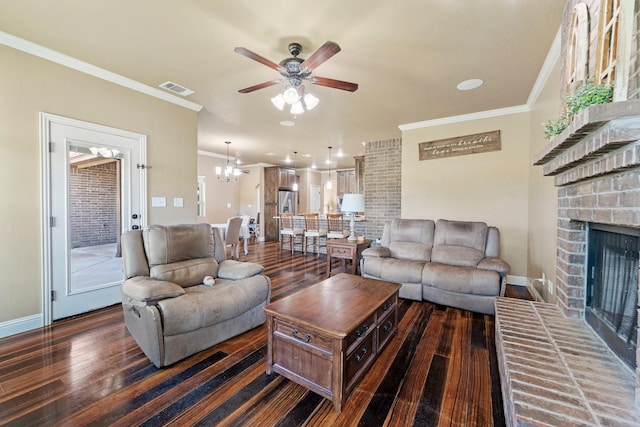 living area with hardwood / wood-style floors, ceiling fan with notable chandelier, ornamental molding, a brick fireplace, and visible vents