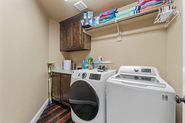 clothes washing area featuring dark wood-style floors, washing machine and dryer, baseboards, visible vents, and cabinet space