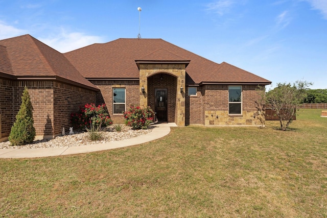 ranch-style home with brick siding, a shingled roof, and a front yard