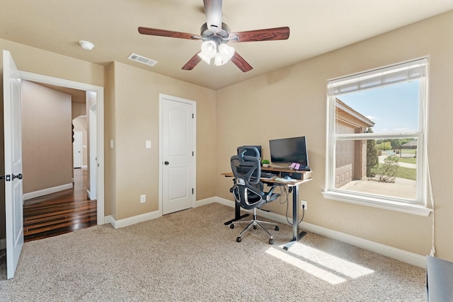office with baseboards, visible vents, carpet, and ceiling fan