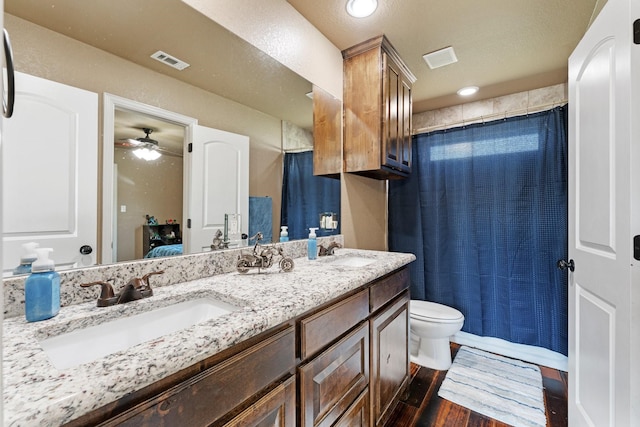 bathroom featuring wood finished floors, visible vents, toilet, and a sink