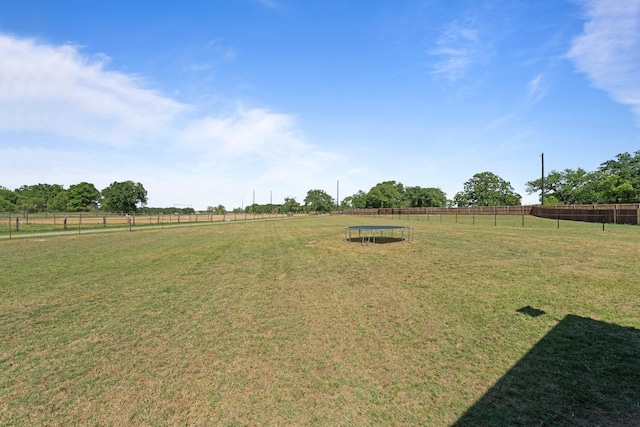 view of yard with fence, a rural view, and a trampoline