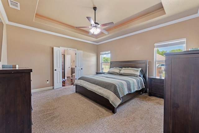 bedroom with a raised ceiling, visible vents, carpet floors, crown molding, and baseboards