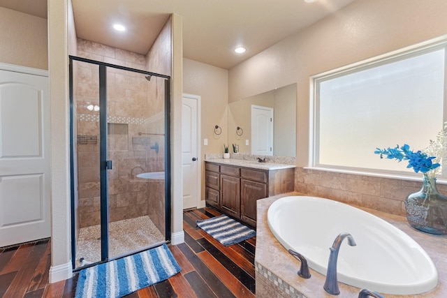 bathroom featuring a bath, wood finished floors, vanity, and a stall shower