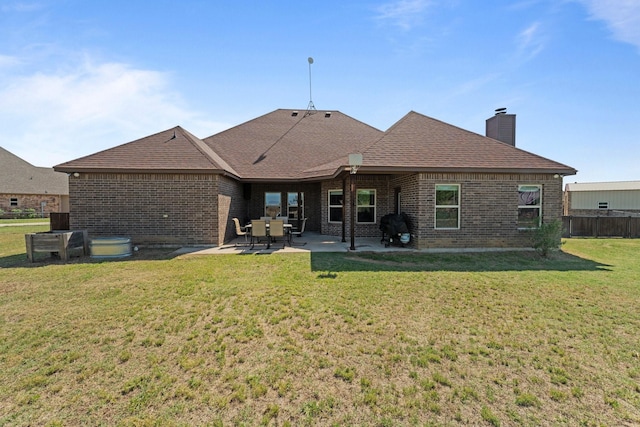 rear view of property with a patio area, a chimney, fence, a yard, and brick siding