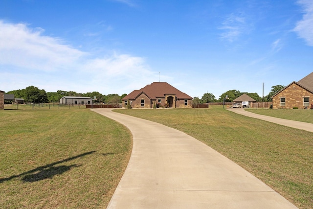 view of property's community with concrete driveway, fence, and a yard