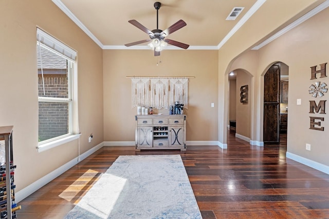 interior space featuring arched walkways, visible vents, a ceiling fan, wood finished floors, and ornamental molding