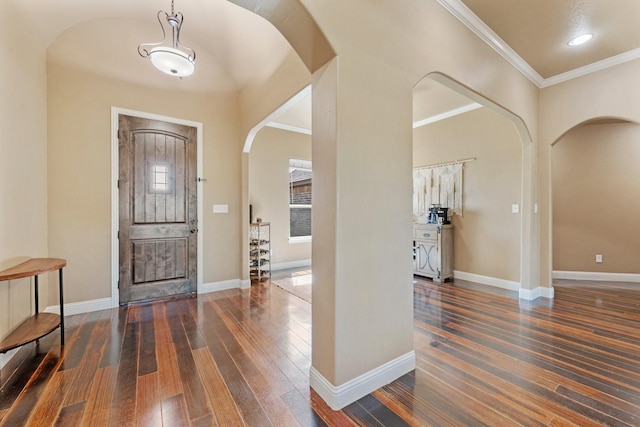 entryway with arched walkways, hardwood / wood-style floors, crown molding, and baseboards