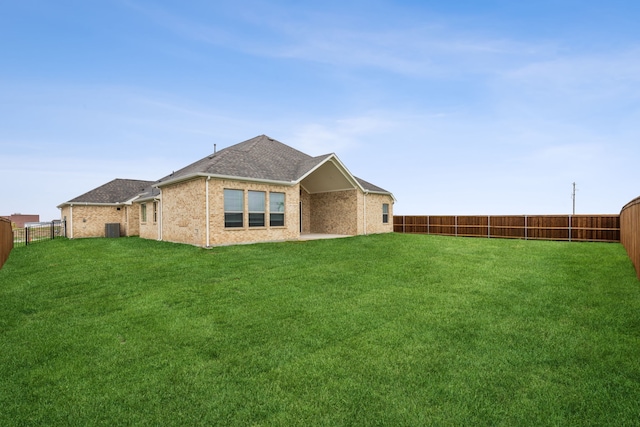 back of property with a lawn, a fenced backyard, roof with shingles, and central air condition unit