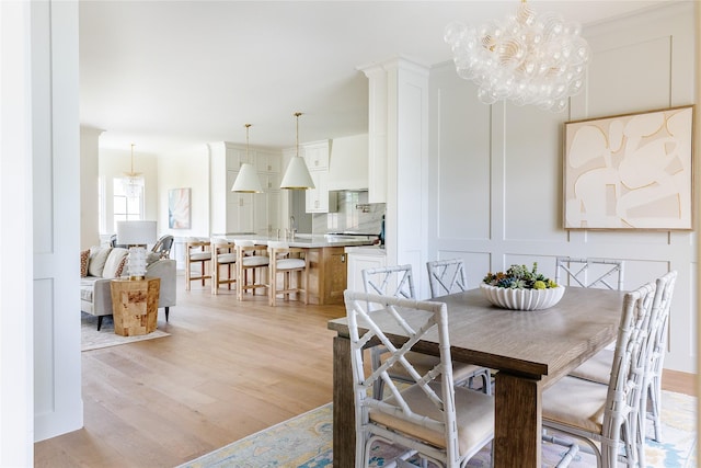 7206 Northaven Rd, Dallas, TX 75230 - dining area with light wood finished floors, an inviting chandelier, and a decorative wall