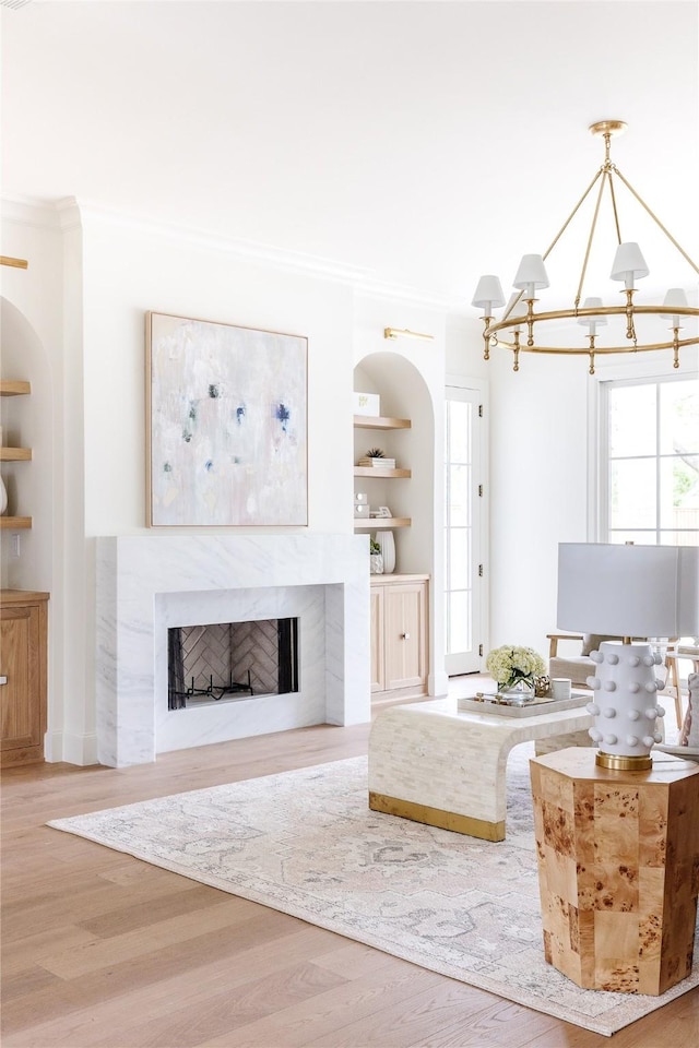 7206 Northaven Rd, Dallas, TX 75230 - living room featuring built in features, an inviting chandelier, wood finished floors, ornamental molding, and a high end fireplace