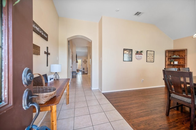 interior space with vaulted ceiling, baseboards, arched walkways, and light tile patterned flooring