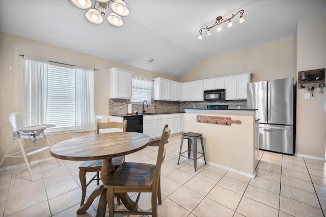 kitchen featuring vaulted ceiling, tasteful backsplash, a sink, black appliances, and light tile patterned flooring