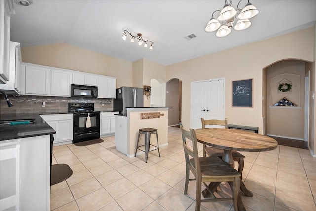 kitchen featuring visible vents, a sink, arched walkways, black appliances, and tasteful backsplash
