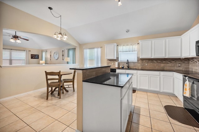kitchen with dark countertops, vaulted ceiling, a sink, a kitchen island, and black appliances
