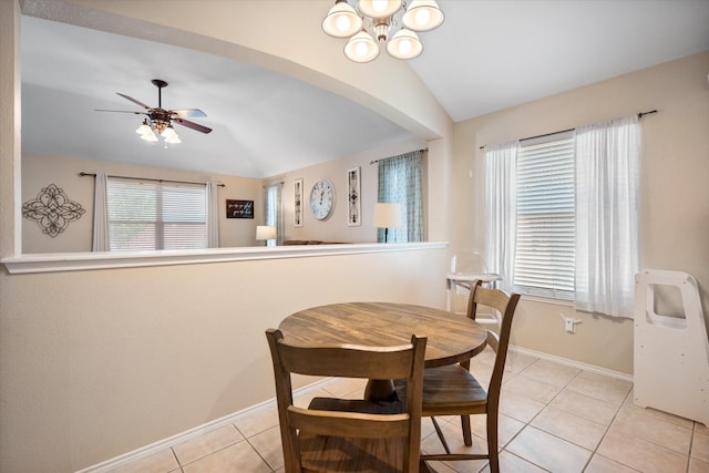 dining space featuring baseboards, vaulted ceiling, ceiling fan with notable chandelier, and light tile patterned floors