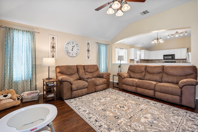 living room with ceiling fan with notable chandelier, vaulted ceiling, visible vents, and dark wood finished floors