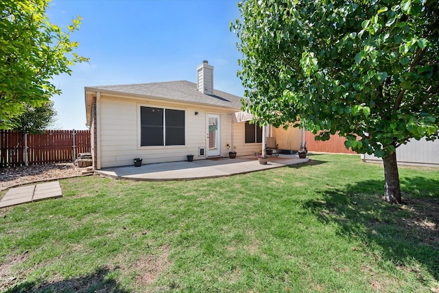 rear view of house with a chimney, a lawn, a fenced backyard, a patio, and roof with shingles