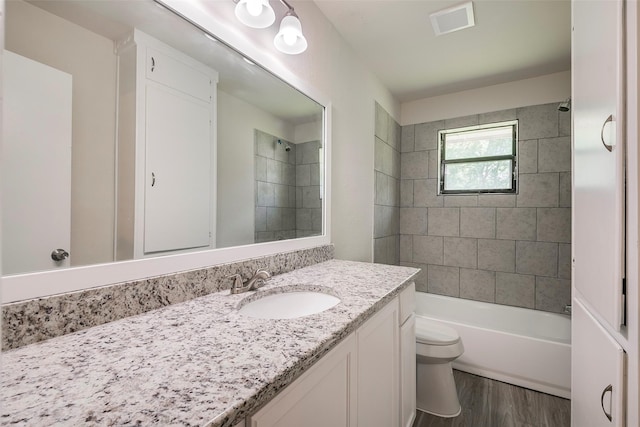 bathroom featuring toilet, visible vents, shower / bath combination, wood finished floors, and vanity