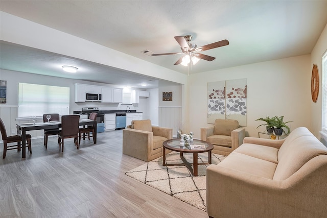 living room with plenty of natural light, a ceiling fan, visible vents, and light wood-style flooring