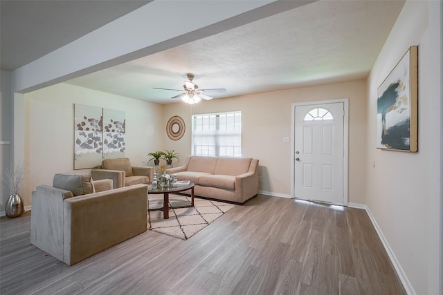 living area featuring ceiling fan, baseboards, and wood finished floors