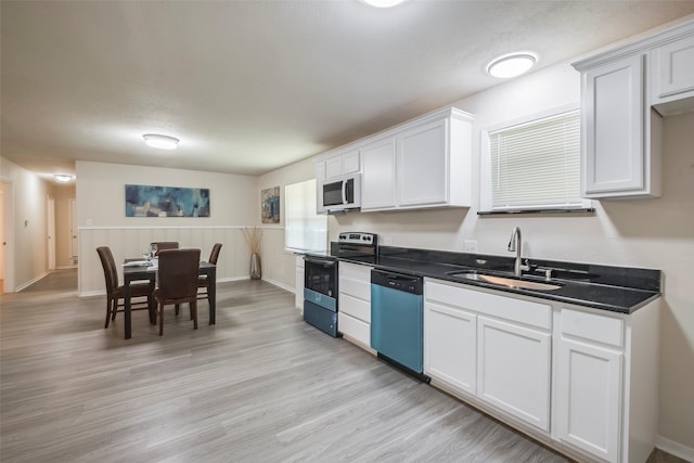 kitchen featuring dishwashing machine, a sink, light wood-style floors, white microwave, and stainless steel electric range